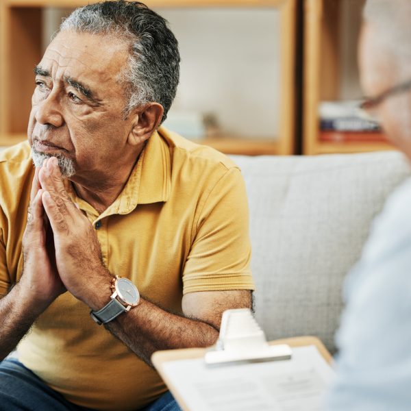 Elderly man talking to a psychologist at a mental health, psychology and therapy clinic for session. Psychological therapist with clipboard for counseling checklist with senior male patient in office