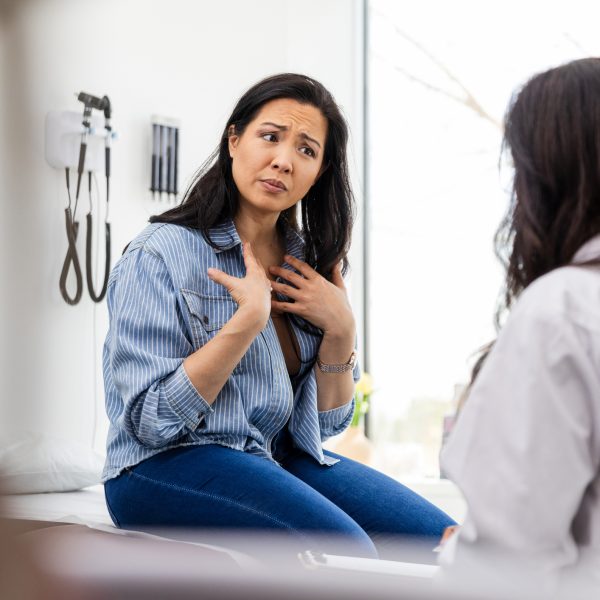 Gesturing toward herself, the distraught mid adult woman tells the gaslighting doctor that it's not all in her head